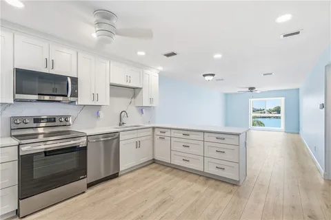 a kitchen with stainless steel appliances sink cabinets and wooden floor