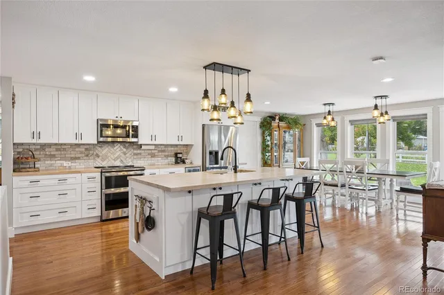 a open kitchen with stainless steel appliances granite countertop a stove and white cabinets with wooden floor