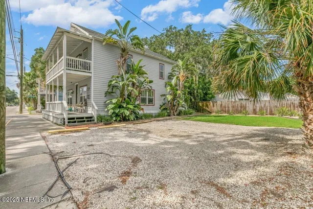 a view of a house with a yard and palm trees