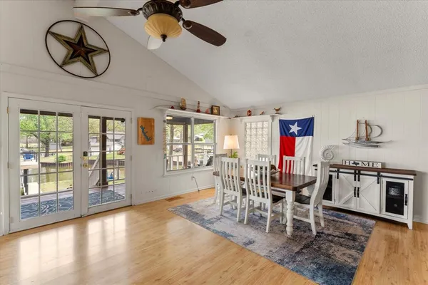 a dining room with wooden floor a chandelier a wooden table and chairs