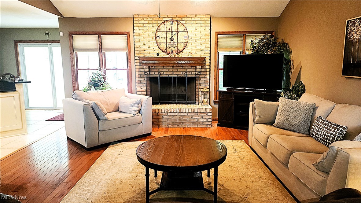 8329 Seasons Road Streetsboro, OH 44241 - Photo 16 of 35 Living room with brick wall, a fireplace, lofted ceiling, and wood-type flooring