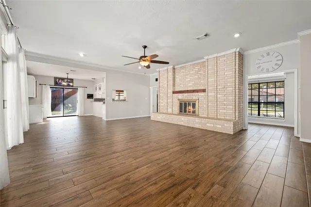 an empty room with wooden floor fireplace and windows