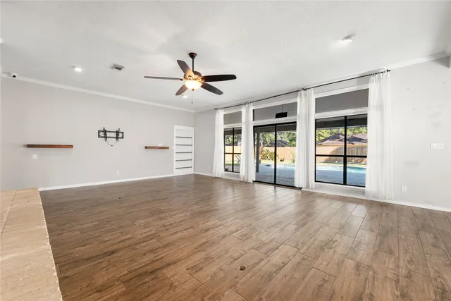 a view of an empty room with a window and wooden floor