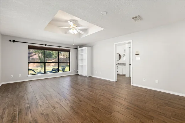 an empty room with wooden floor and windows