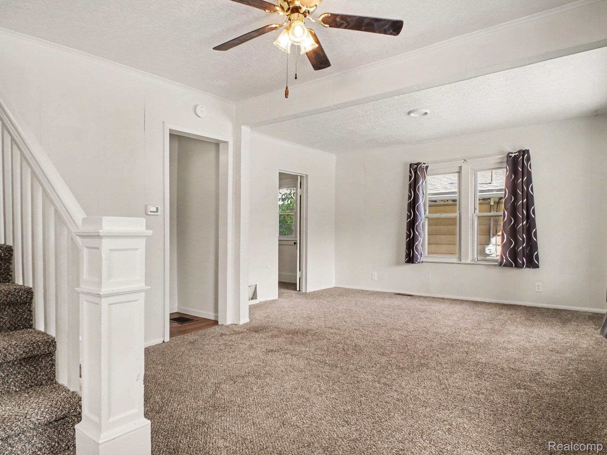2840 Miller Road Flint, MI 48503 - Photo 7 of 49 Expansive room with neutral carpet, a ceiling fan with light, and architectural ceiling beams