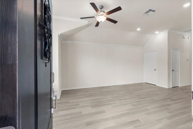 an empty room with wooden floor and a ceiling fan window