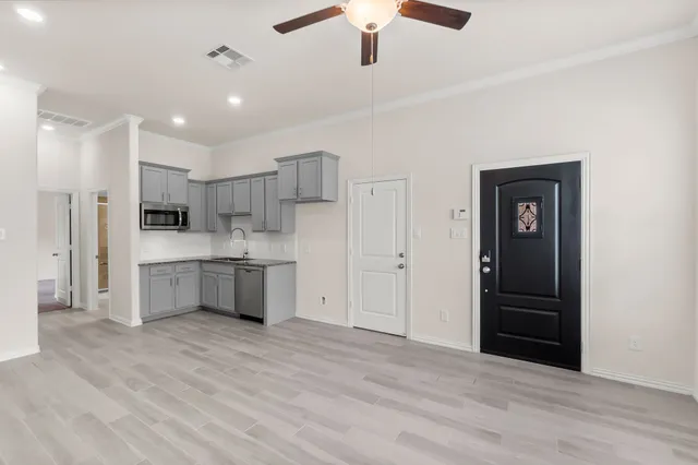 a large white kitchen with stainless steel appliances granite countertop a refrigerator and a sink