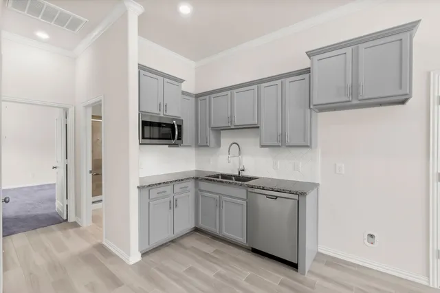 a kitchen with stainless steel appliances granite countertop white cabinets a sink a stove a refrigerator and a microwave