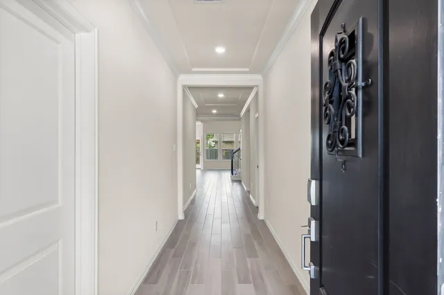 a view of a hallway with wooden floor and a bathroom