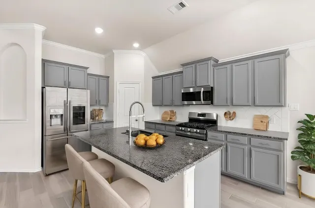 a kitchen with stainless steel appliances granite countertop a sink stove refrigerator and microwave