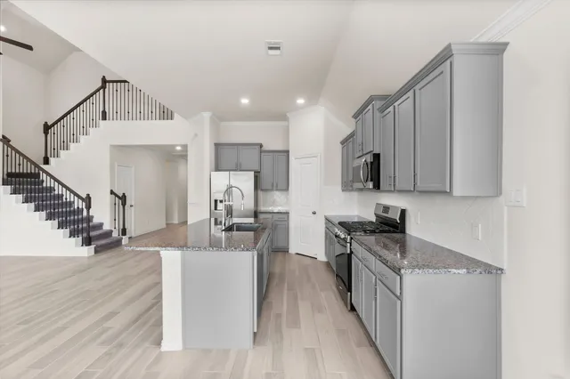 a kitchen with stainless steel appliances granite countertop a refrigerator a sink dishwasher a s stove top oven a dining table and chairs with wooden floor