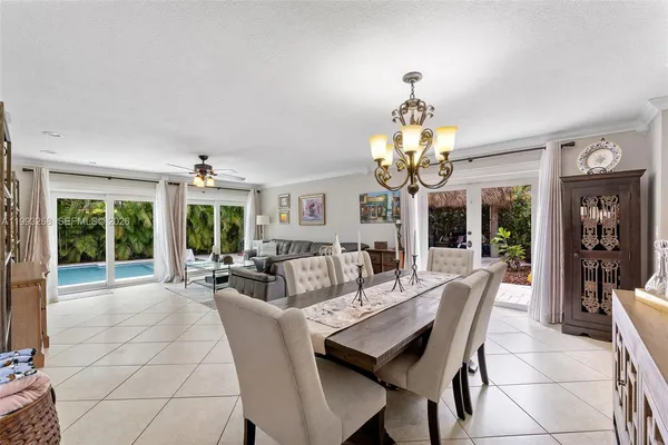 a dining room with wooden floor a chandelier a glass table and chairs