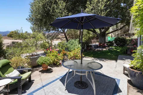 a view of a backyard with table and chairs under an umbrella