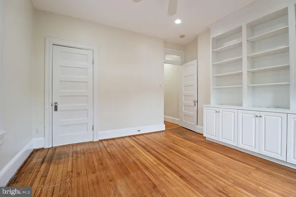 an empty room with wooden floor fan and windows