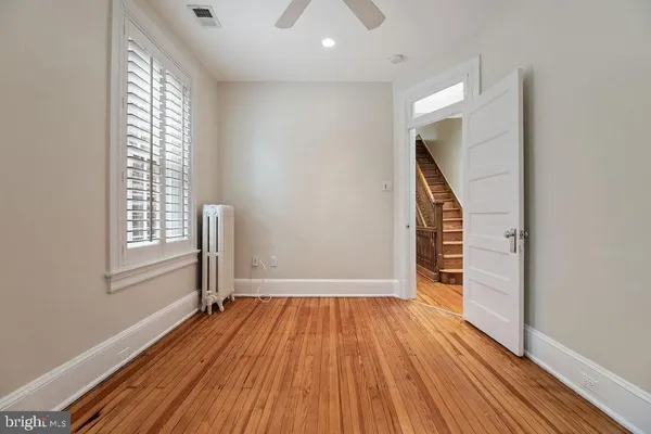 a view of an empty room with a window and wooden floor