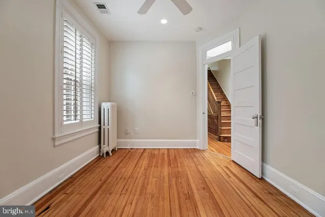 a view of an empty room with a window and wooden floor