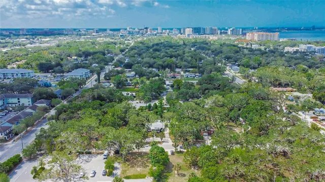 an aerial view of a residential houses with outdoor space and trees
