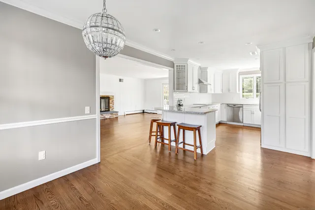 a dining room with stainless steel appliances granite countertop furniture wooden floor a chandelier and kitchen view