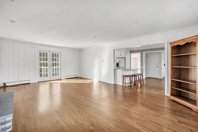 a view of an empty room with window and wooden floor