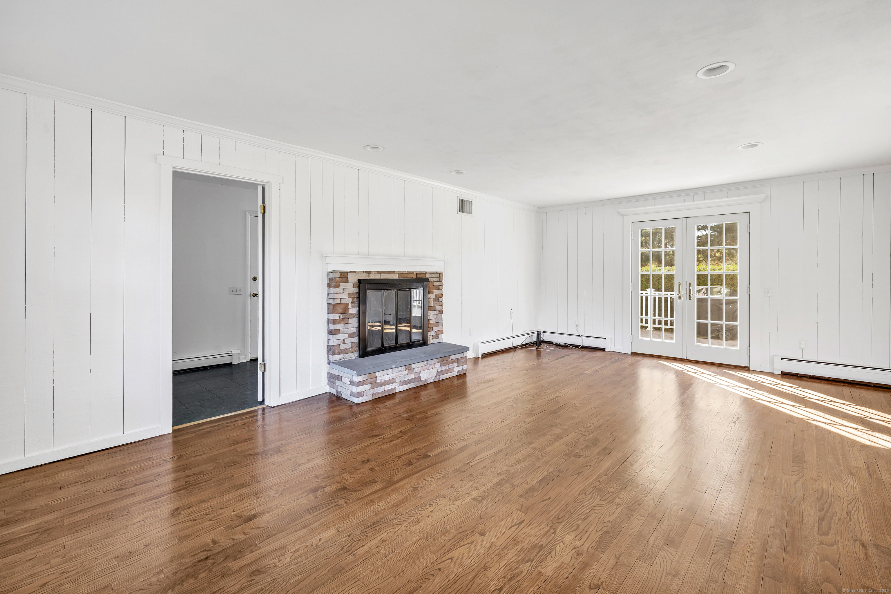 41 Butternut Lane Fairfield, CT 06890 - Photo 15 of 33 an empty room with wooden floor fireplace and windows