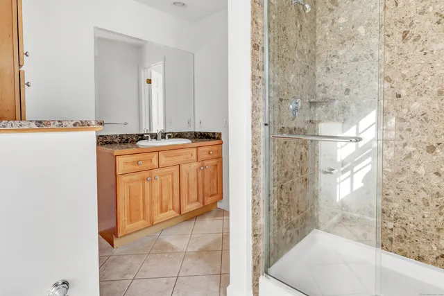 a bathroom with a granite countertop sink a mirror and a shower