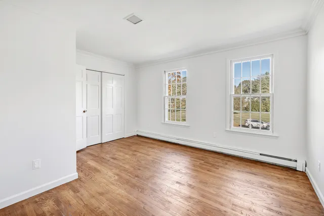 an empty room with wooden floor and windows