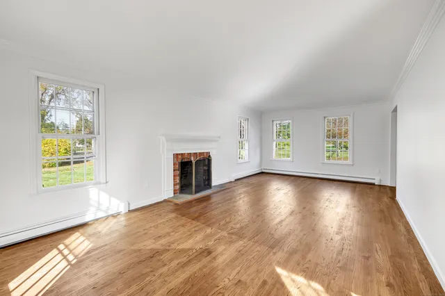 a view of an empty room with window and wooden floor