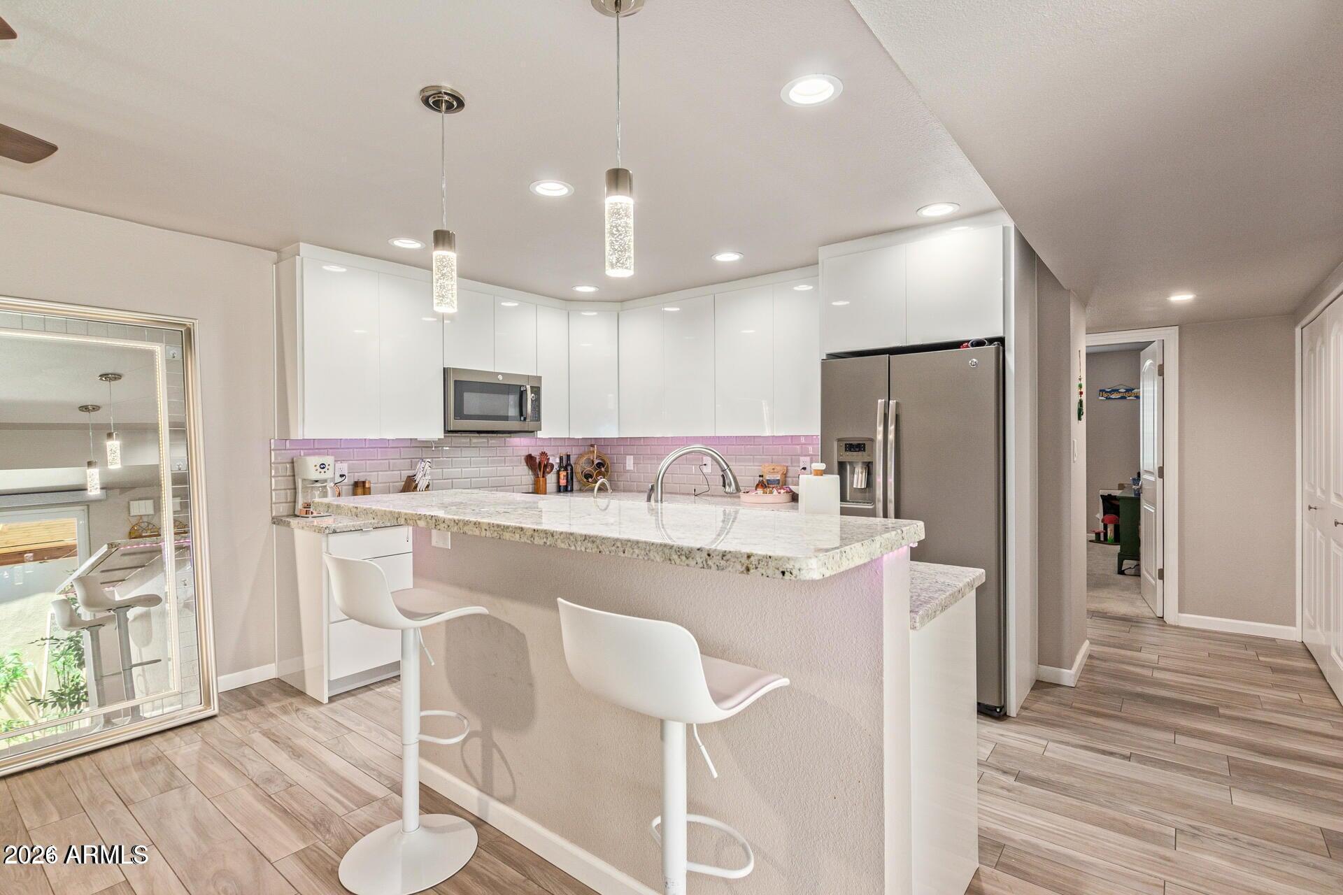 5913 East Thomas Road Scottsdale, AZ 85251 - Photo 4 of 26 a kitchen with kitchen island stainless steel appliances a refrigerator a stove a sink dishwasher with a dining table and chairs with wooden floor