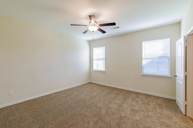 an empty room with a hallway and a chandelier fan