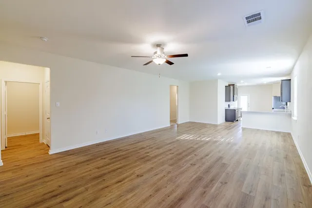 a view of empty room with wooden floor and ceiling fan