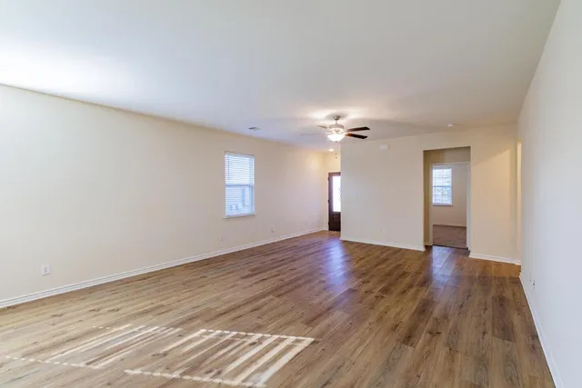 a view of an empty room with wooden floor and window