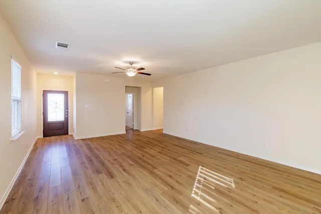 a view of an empty room with wooden floor and a window