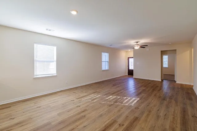 a view of an empty room with wooden floor and a window