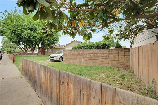 a view of a street next to a yard with wooden fence