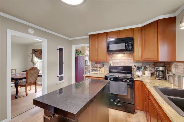 a kitchen with stainless steel appliances a stove a sink a microwave a dining table and chairs