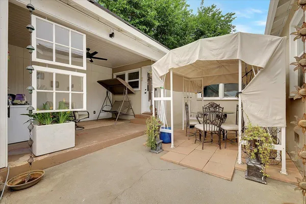 a view of a patio with table and chairs near a barbeque