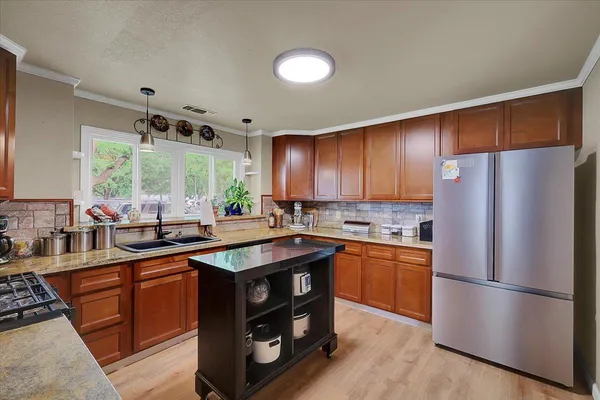 a kitchen with stainless steel appliances granite countertop a refrigerator a sink dishwasher a stove and a refrigerator