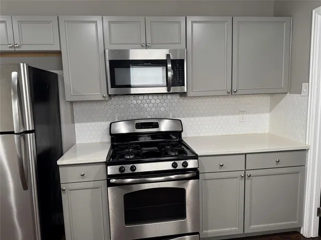 a kitchen with stainless steel appliances white cabinets and a stove a refrigerator with wooden floors