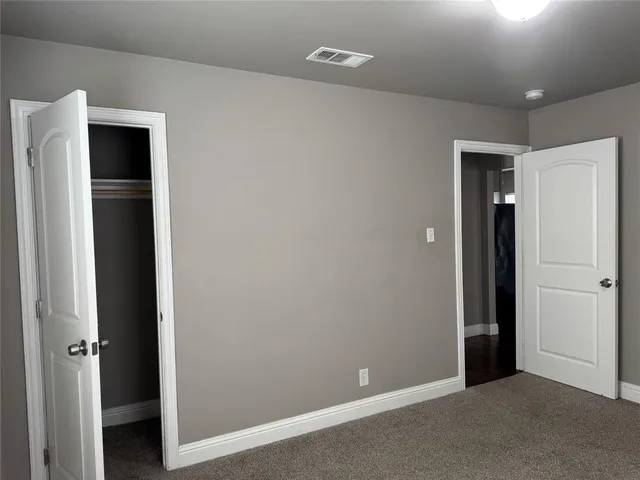 an empty room with closet and a hallway