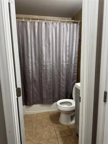 a bathroom with a toilet and a shower curtain
