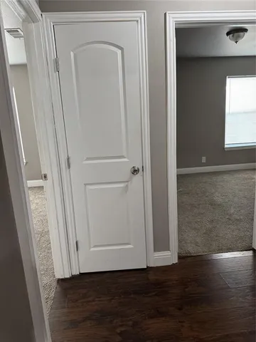 a view of a hallway with wooden floor and a cabinet