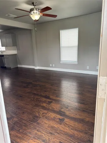 an empty room with wooden floor chandelier fan and windows