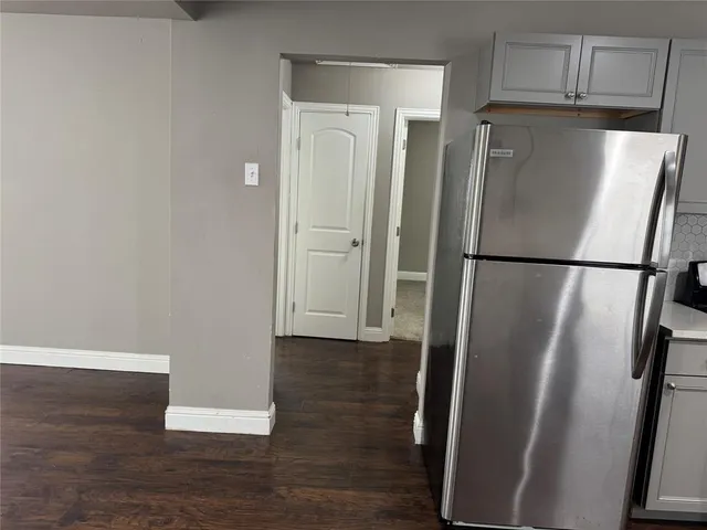 a view of a refrigerator in kitchen and an empty room
