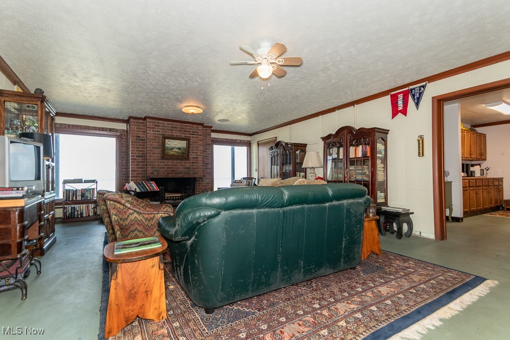 7563 Salida Road Mentor, OH 44060 - Photo 27 of 48 Living room with ceiling fan, ornamental molding, a brick fireplace, and a textured ceiling