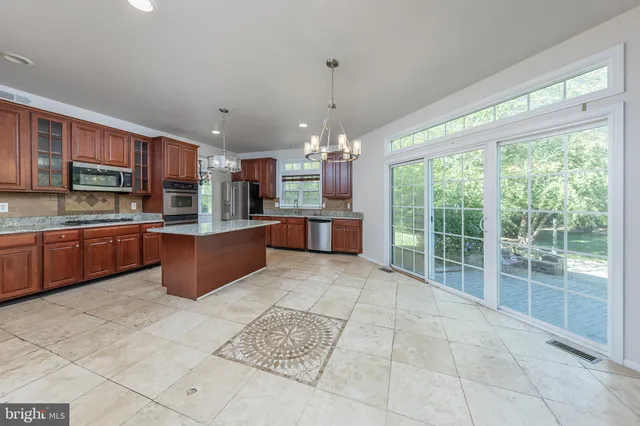 a large kitchen with stainless steel appliances granite countertop a stove granite counter tops and a view of living room