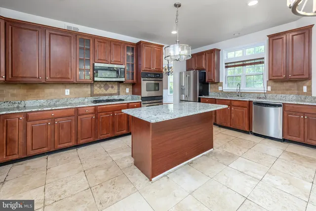 a kitchen with stainless steel appliances granite countertop a stove a sink and a microwave