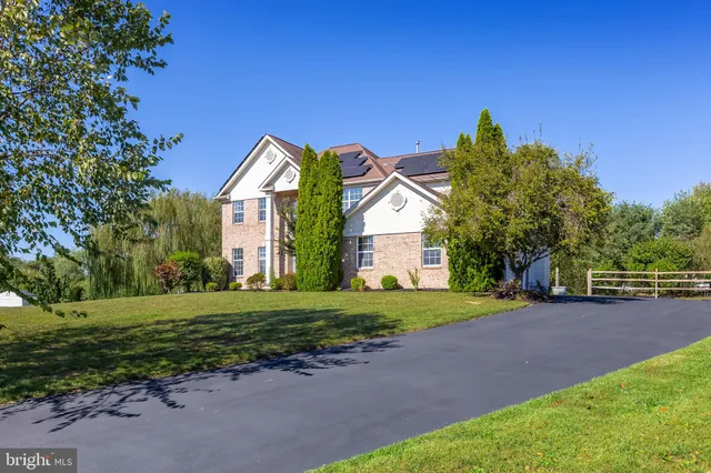 a view of a big house with a big yard and large trees