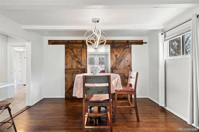 a dining room with wooden floor a chandelier a glass table and chairs