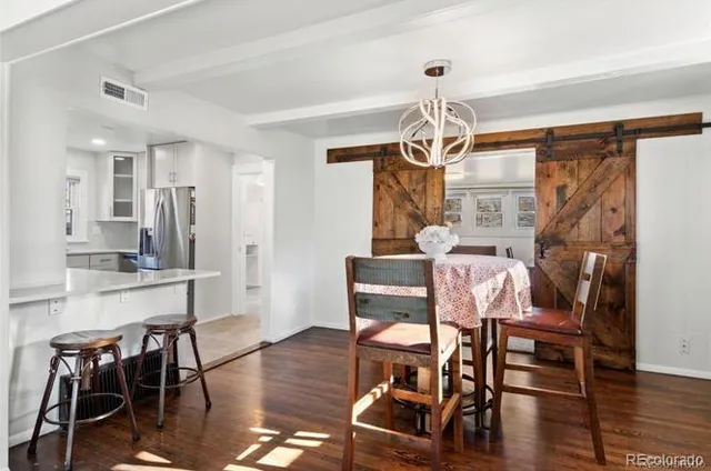 a dining room with wooden floor a chandelier a glass table and chairs