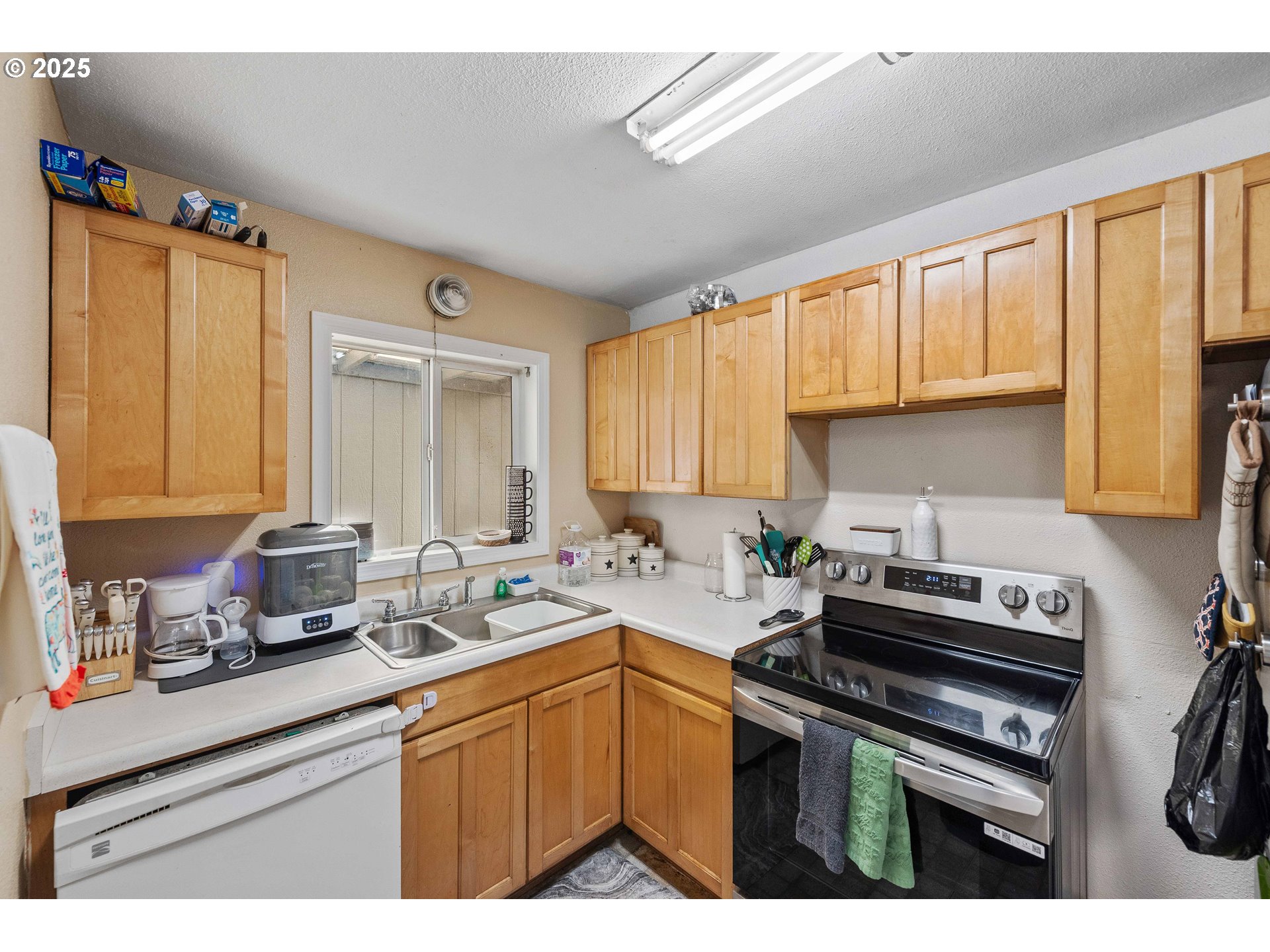 805 C Street Myrtle Point, OR 97458 - Photo 19 of 30 a kitchen with stainless steel appliances a sink a stove a refrigerator cabinets and a window